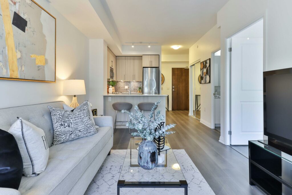 a living room with a couch and a coffee table with vase on top that has eucalyptus inside