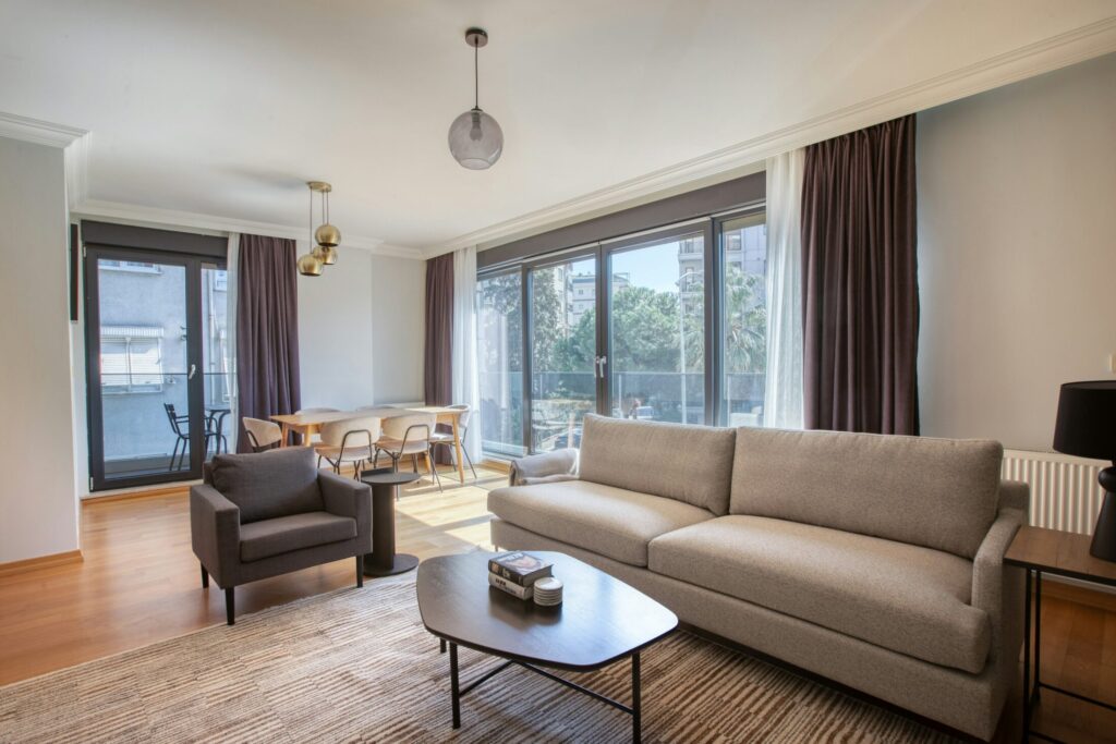 a living room filled with furniture and a large window with brown and white curtains